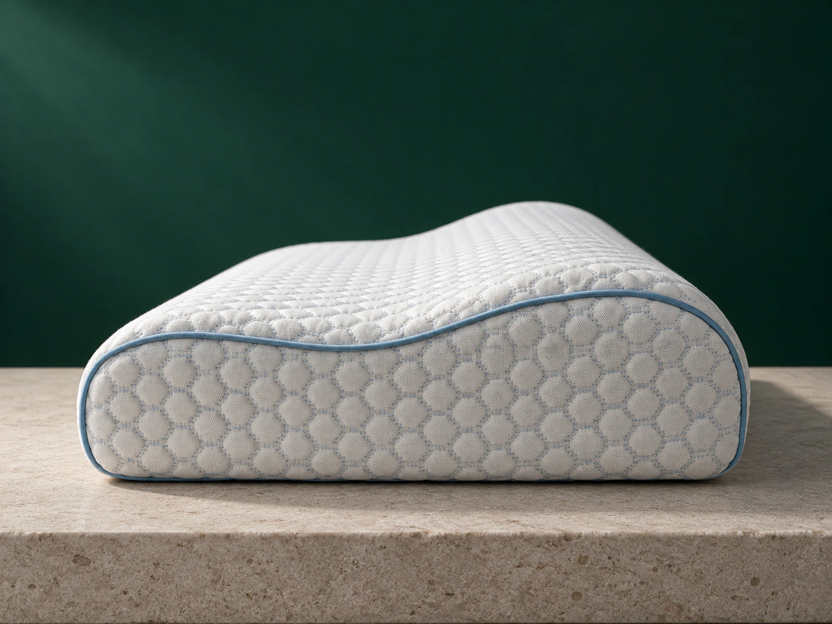 Das ERGO PILLOW mit ungleich hohen Längsseiten im seitlichen Profil vor dunkelgrünem Hintergrund