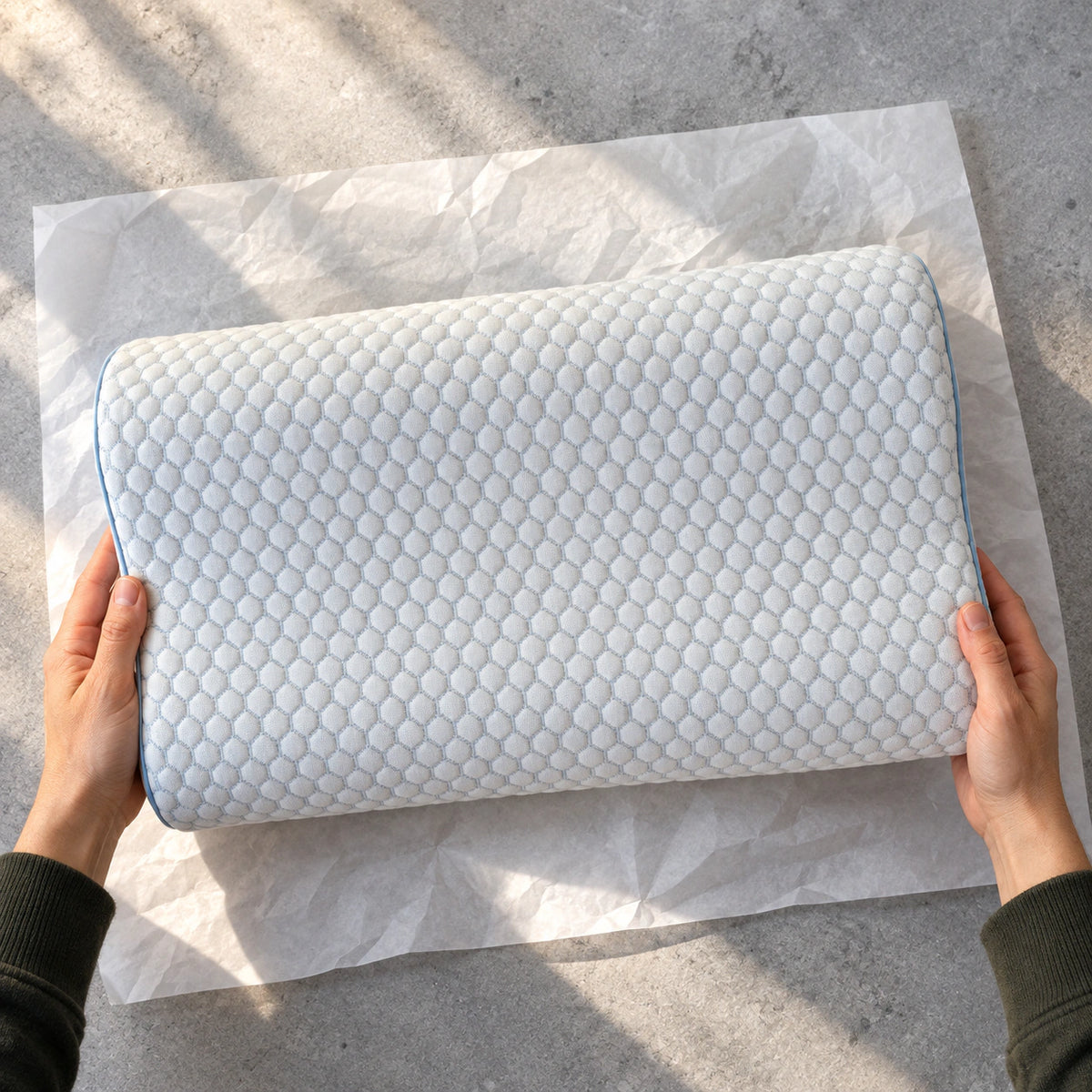 Hände heben das vollständig entfaltete ERGO PILLOW aus geöffnetem weißem Papier